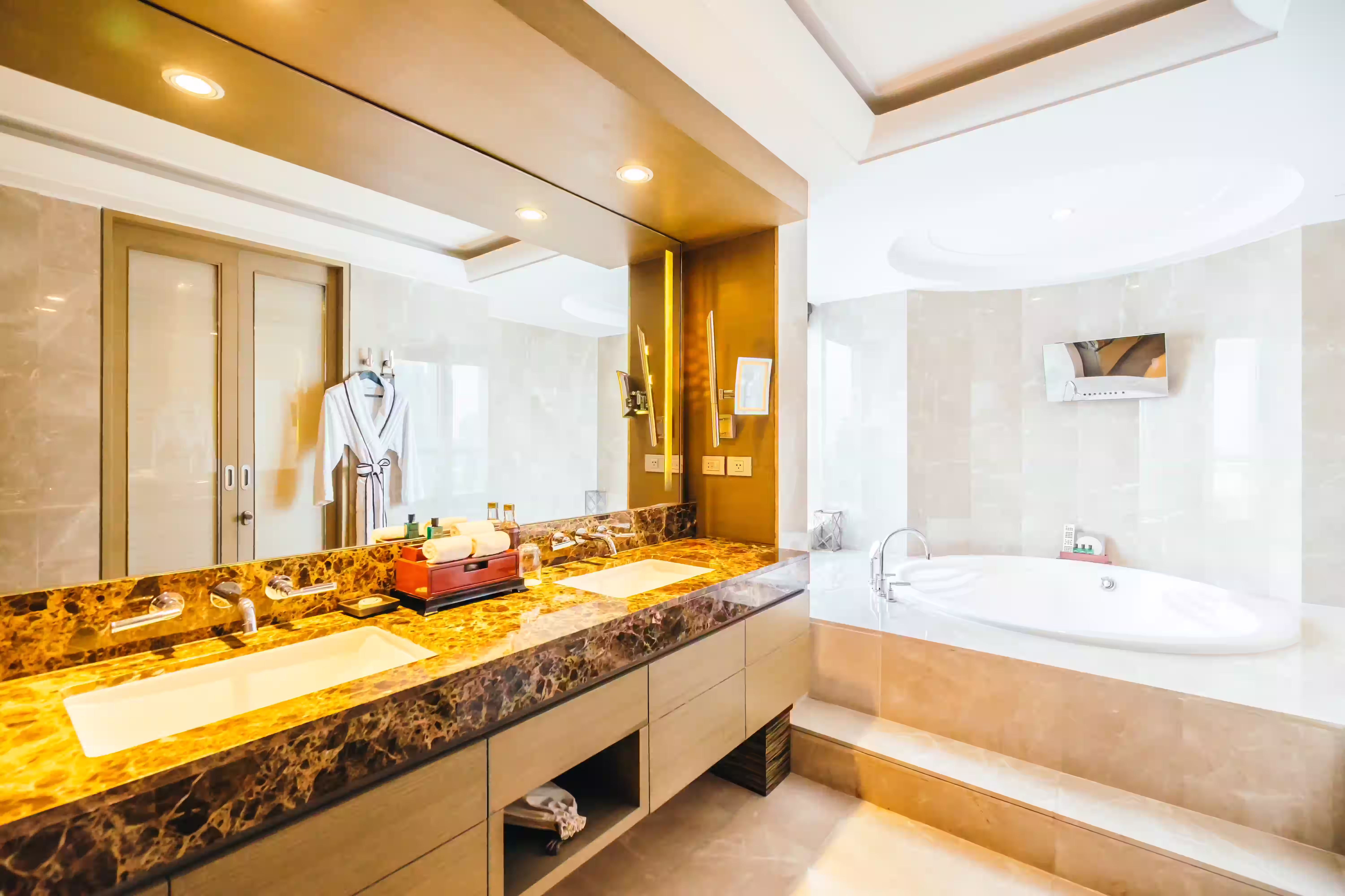 Modern bathroom with marble countertop, two sinks, large mirror, and glass shower enclosure with towels.
